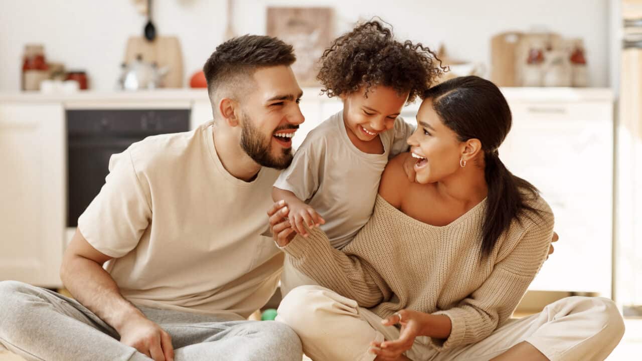 Fortify Your Roof - Protect What Matters Most Picture of a happy family sitting on the floor in the kitchen of their home.